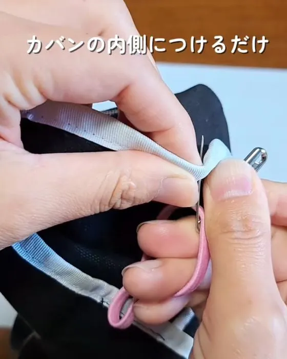 ゴムを通した安全ピンをカバンにつけている様子