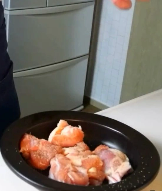 鶏肉に塩コショウをまぶす様子
