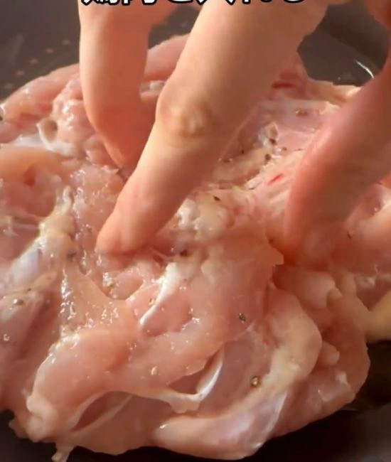 フライパンに鶏もも肉を入れる様子