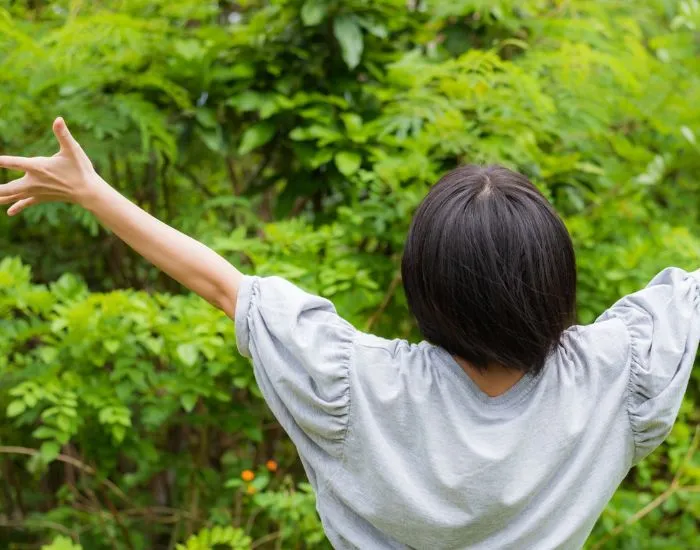 自然のなかで手を挙げている女性