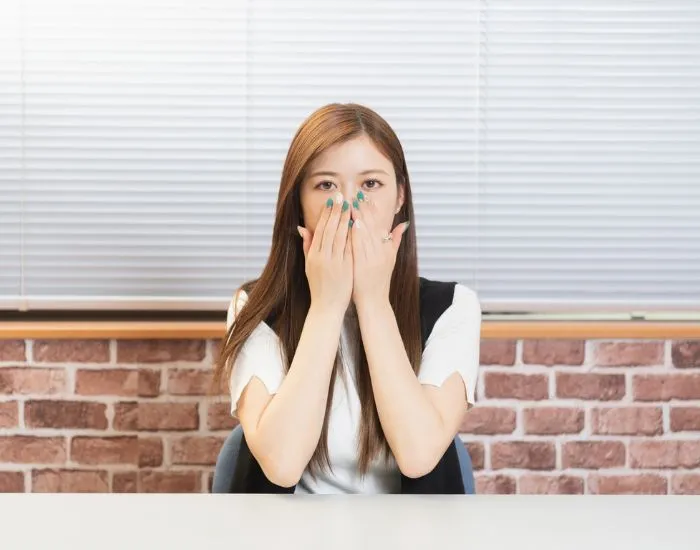 手で口を覆っている女性