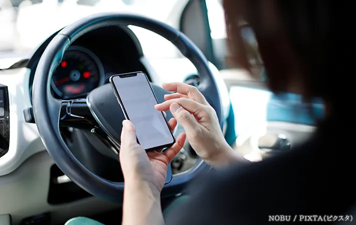 社内でスマホを操作する人の写真