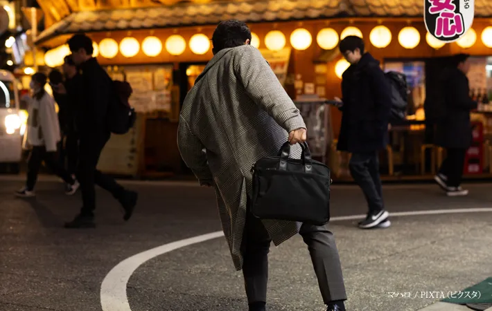 『夜の繁華街で酔っ払う男性』の写真