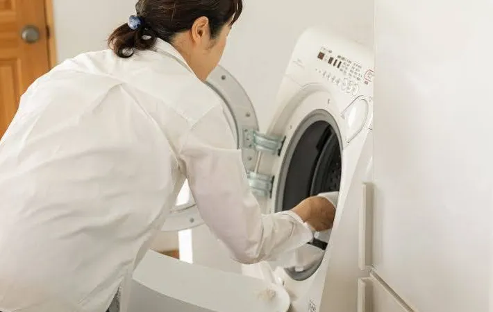 『洗濯機から衣類を取り出す女性』の写真（撮影：Heulie）