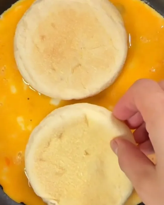 焼いた卵にイングリッシュマフィンを置く様子