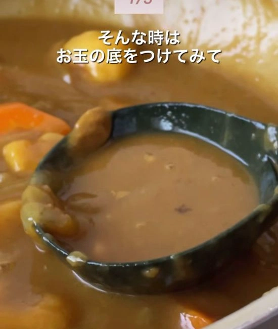 お玉の底をカレーにつける様子