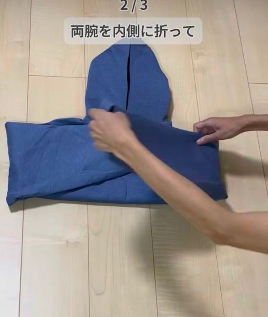 パーカーの両腕部分を折る様子