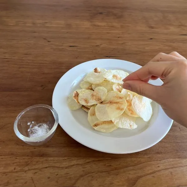 ノンオイルポテトチップスに塩を振りかけている様子（撮影：grapeフード編集部）