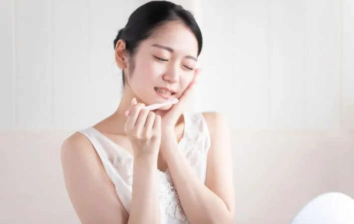 歯磨き中に痛みを感じる女性の写真