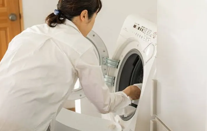 『洗濯機に洗濯物を入れる女性』の写真（撮影：Heulie）