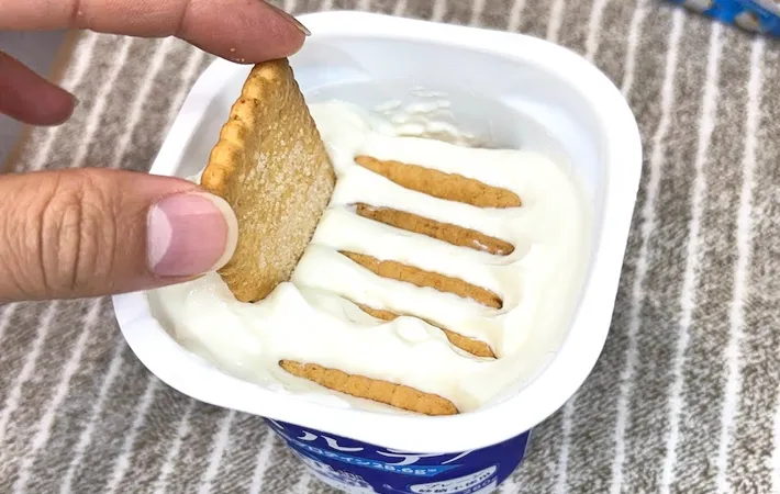 『ココナッツサブレ』をヨーグルトに入れる写真（撮影：キジカク）