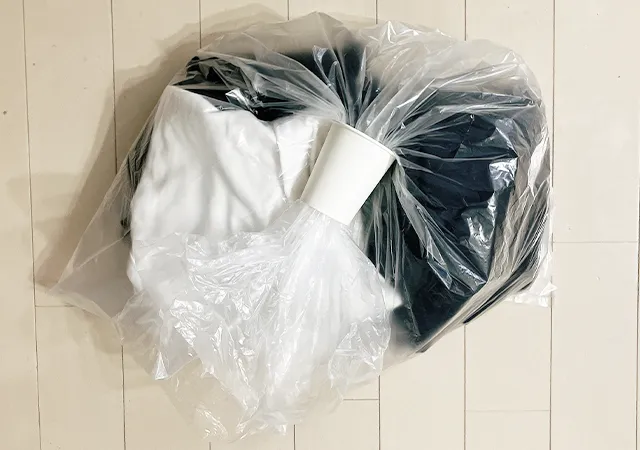 ゴミ袋に服を入れて紙コップを開き口に通す（撮影：grapeライフハック編集部）