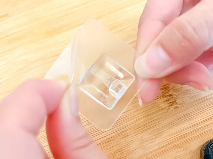 『貼ってはがせるシートフック（クリア、6個）』のシートをはがすの写真（撮影：キジカク）