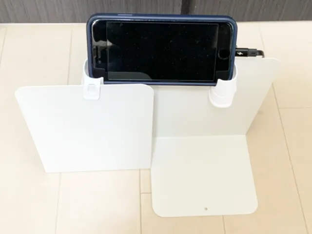 『薬味チューブキャップ（フック付）』をブックエンドに引っかけ、充電中のスマホを置く（撮影：grapeライフハック編集部）