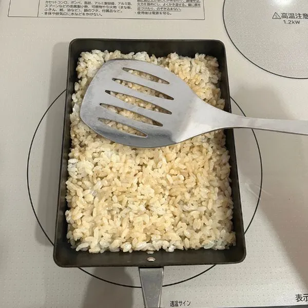 ご飯をフライ返しで押しつけている様子（撮影：grapeフード編集部）