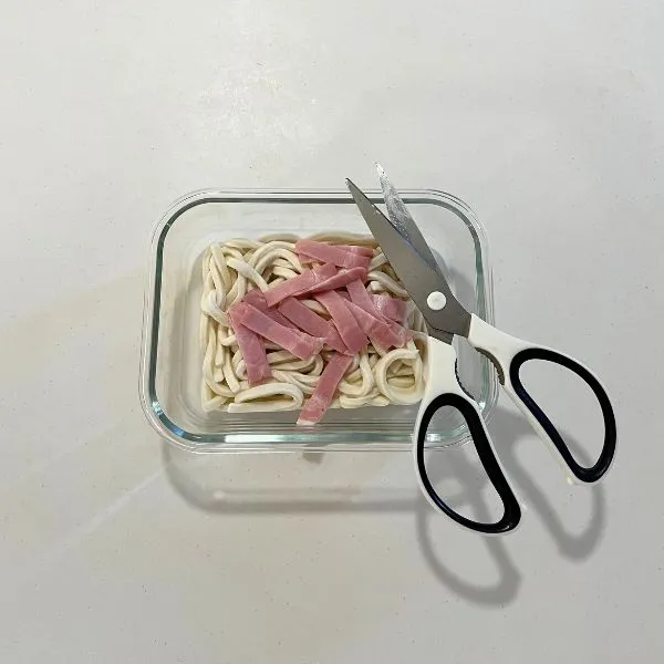 耐熱容器に冷凍うどんと切ったベーコンを入れた写真（撮影：grapeフード編集部）