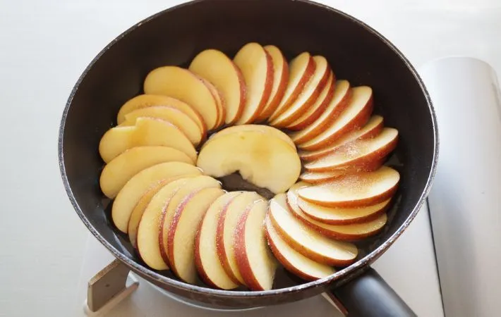 フライパンに並べられたリンゴの写真