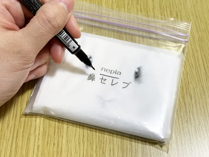 ジッパーつきの保存袋にポケットティッシュを入れ、取り出し口になる部分にマークを入れている画像（撮影：grapeライフハック編集部）