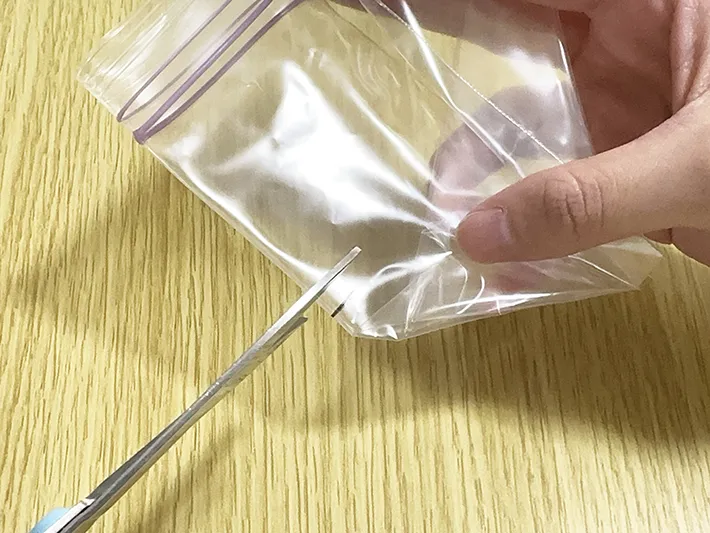 マークをつけたジッパーつき保存袋をハサミで切ろうとしている画像（撮影：grapeライフハック編集部）