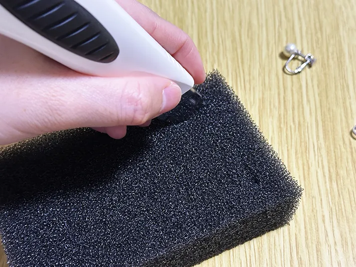 食器用スポンジにイヤリング用の切り込みを入れている画像（撮影：grapeライフハック編集部）