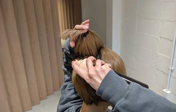 髪を持ち上げ裏側からスプレーする写真