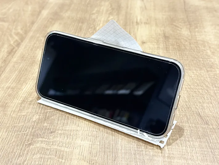 紙で作ったスマホスタンドに『iPhone 16』を立てた画像（撮影：grapeライフハック編集部）