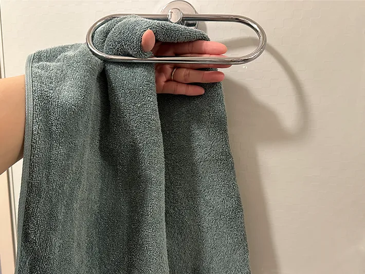 2つ折りにしたタオルを手にかけ、ハンガーラックの後ろ側にまわした画像（撮影：grapeライフハック編集部）