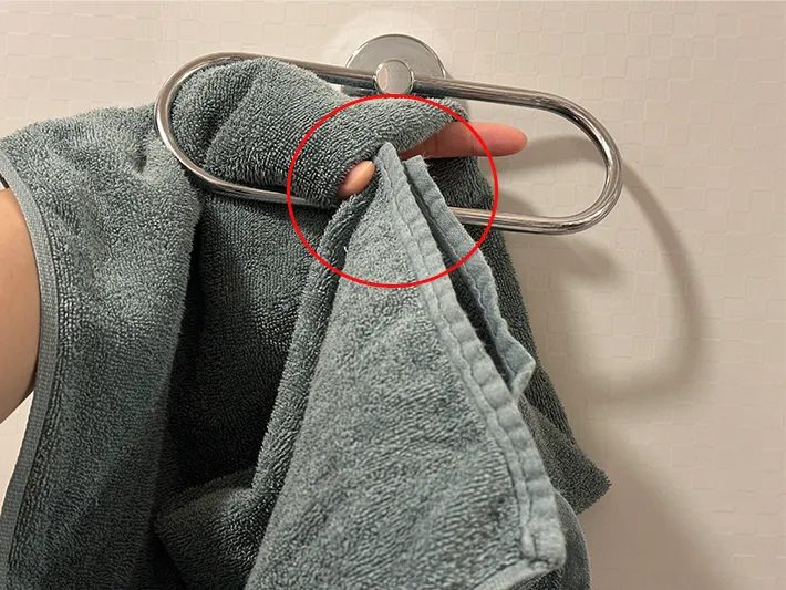 2つ折りにしたタオルを手にかけ、両端を持つ部分を丸で囲った画像（撮影：grapeライフハック編集部）