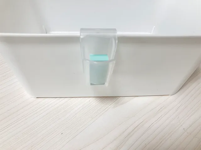 『キャンドゥ』の『薬味チューブホルダー』に付箋を入れて収納ボックスに引っかけた状態（撮影：grapeライフハック編集部）