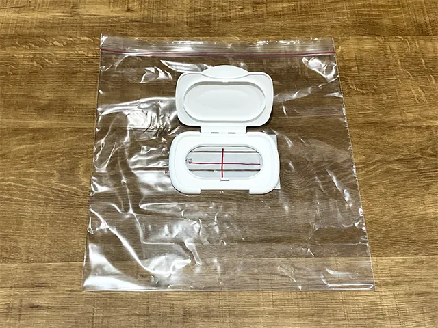 ジッパーつき保存袋の上にウェットシートの蓋を置き、十字を描いた状態（撮影：grapeライフハック編集部）