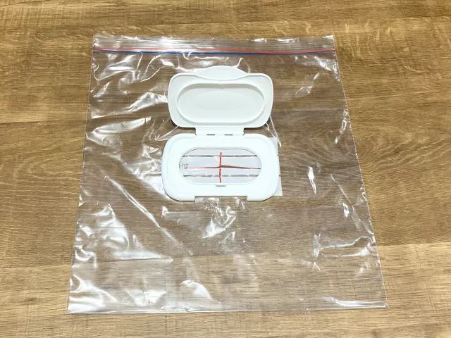 ジッパーつき保存袋の上にウェットシートの蓋を置き、十字を描いた状態（撮影：grapeライフハック編集部）