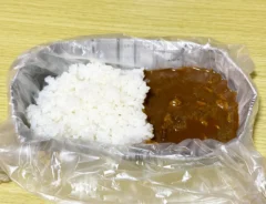 新聞紙で作った皿に『アイラップ』を敷き、その上にカレーをのせた画像（撮影：grapeライフハック編集部）