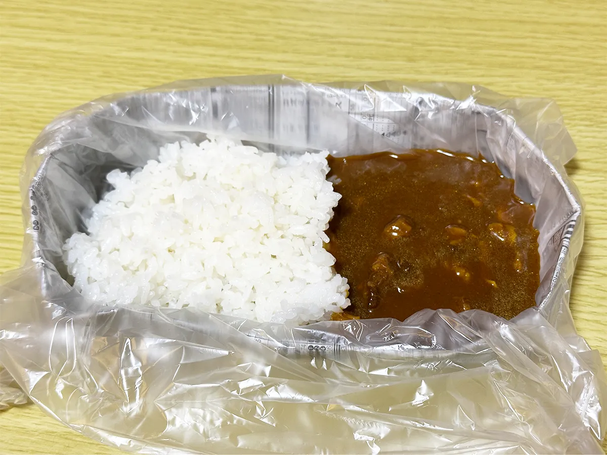 新聞紙で作った皿に『アイラップ』を敷き、その上にカレーをのせた画像(撮影:grapeライフハック編集部)