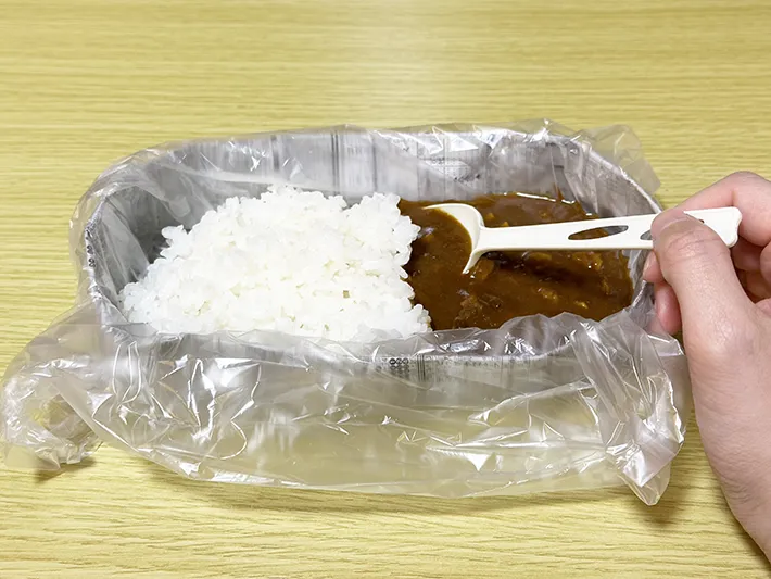 新聞紙で作った皿に『アイラップ』を被せ、その上にご飯とカレーのルーを入れた画像（撮影：grapeライフハック編集部）