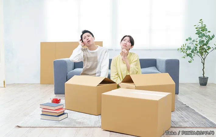 ダンボールの前で悩んでいる男女の写真