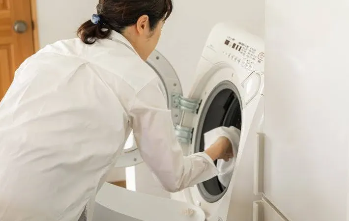 『洗濯物を洗濯槽に入れる女性』の写真（撮影：Heulie）