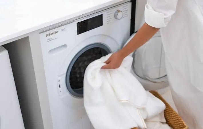 『洗濯機に衣類を入れる女性』の写真（撮影：Heulie）