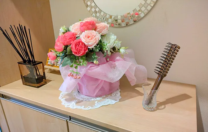 玄関に置いたヘアブラシと花の写真