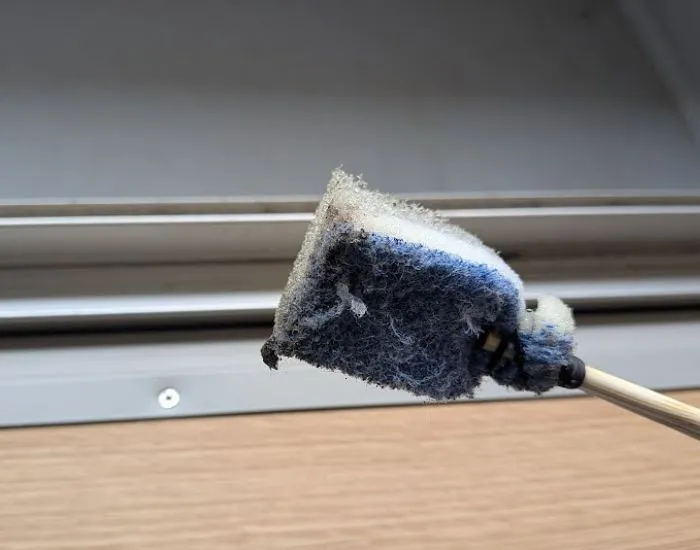 割り箸スポンジでサッシの溝を掃除する様子（撮影：grapeライフハック編集部）
