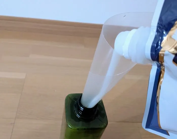 クリアファイルをじょうご代わりにして詰め替える様子