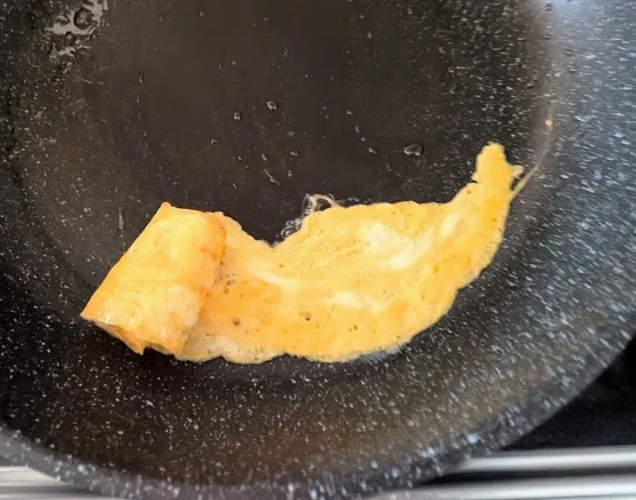 焼いた卵を箸で巻いてバラの形に整えている様子（撮影：grapeフード編集部）