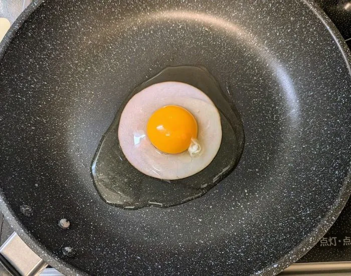 ハムの上に卵を割り入れる様子（撮影：grapeフード編集部）