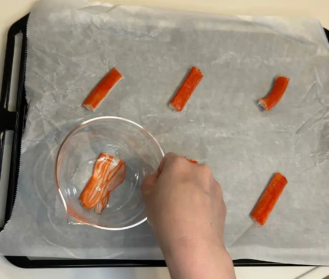 カニカマを押さえて広げている様子（撮影：grapeフード編集部）