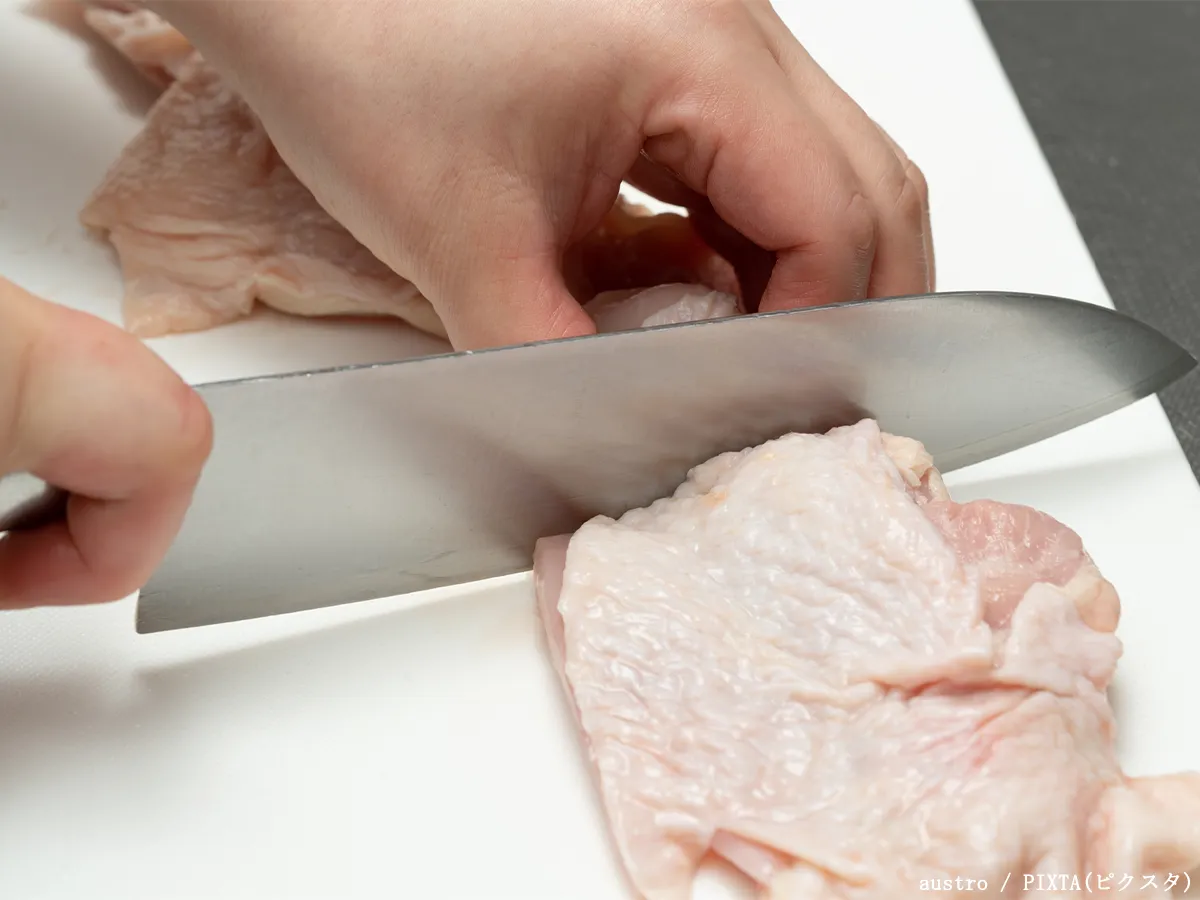 まな板で鶏肉を切る写真