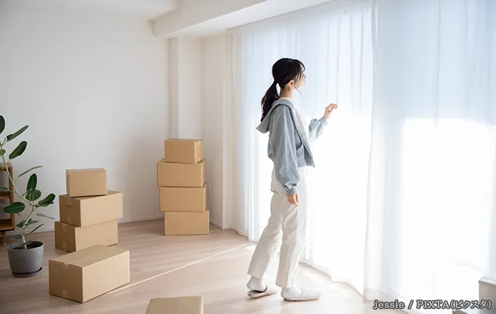 引っ越し業者が来るのを待つ女性の写真