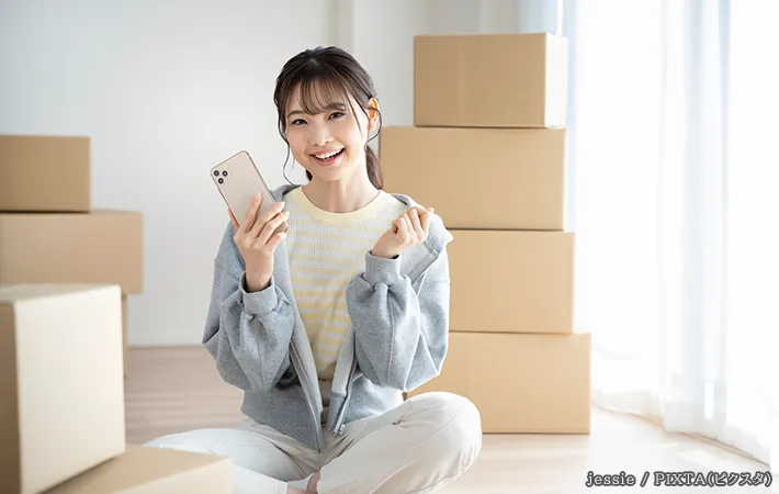 スマホで引っ越し業者の見積もりを確認する女性の写真