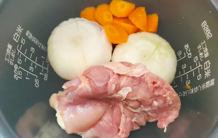 炊飯器に鶏もも肉と新玉ねぎとにんじんが入った画像（撮影：エニママ）