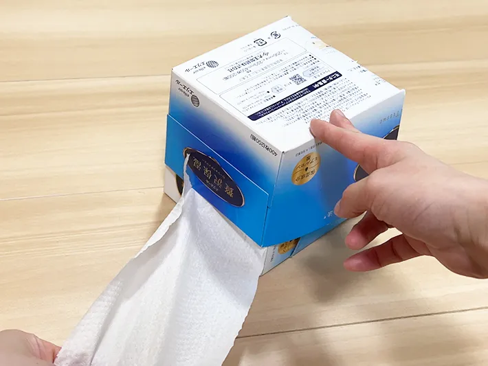トイレットペーパーケースからトイレットペーパーを引き出し、切ろうとしている画像（撮影：grapeライフハック編集部）