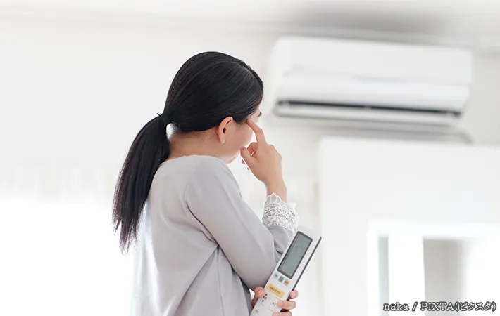 エアコンの前で困っている女性の写真