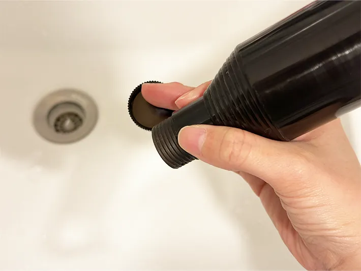 『伸縮傘カバー』の底にあるキャップを外して排水している画像（撮影：grapeライフハック編集部）